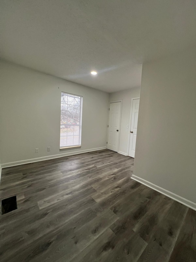 empty room with visible vents, baseboards, and dark wood finished floors