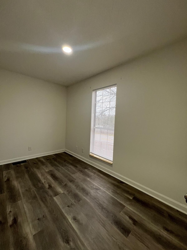 spare room with dark wood-style floors and baseboards