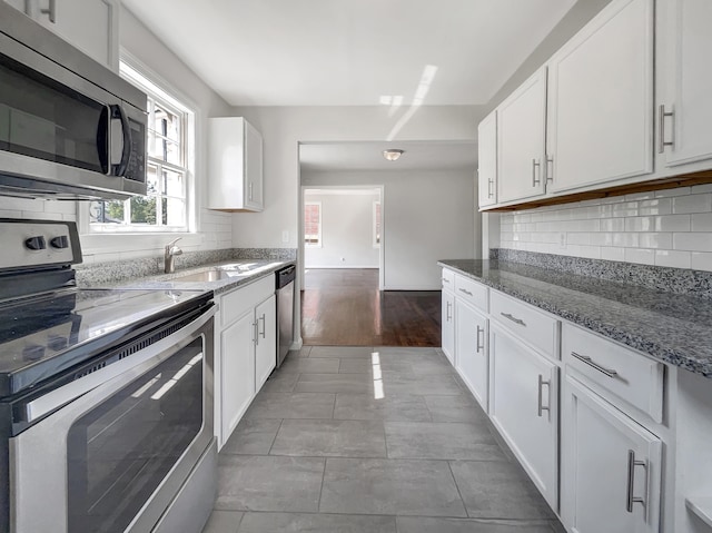 kitchen featuring hardwood / wood-style floors, light stone counters, stainless steel appliances, white cabinetry, and sink