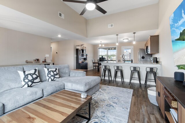 living room with a towering ceiling, ceiling fan, dark wood-type flooring, and sink