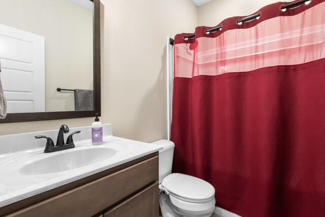 bathroom with curtained shower, vanity, and toilet