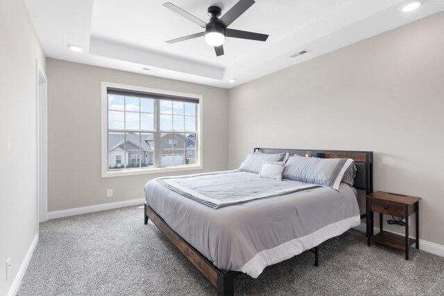 bedroom featuring carpet floors, a raised ceiling, and ceiling fan