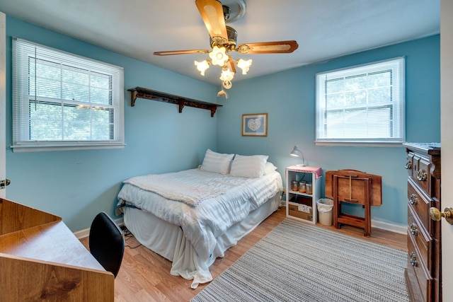 bedroom with ceiling fan, multiple windows, and light hardwood / wood-style floors