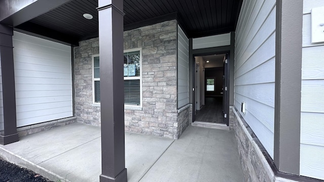 property entrance featuring stone siding and covered porch