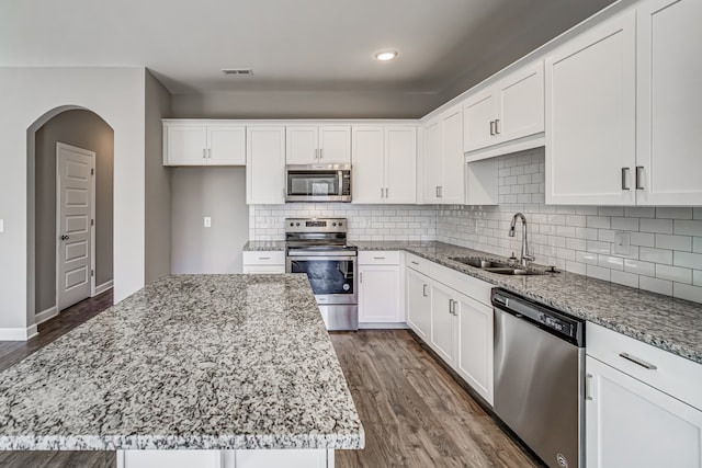 kitchen featuring sink, light stone counters, appliances with stainless steel finishes, a kitchen island, and white cabinets