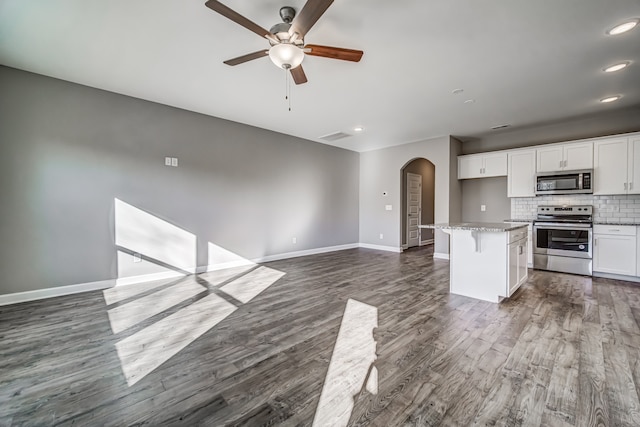 kitchen with stainless steel appliances, dark hardwood / wood-style floors, a kitchen breakfast bar, white cabinets, and a center island