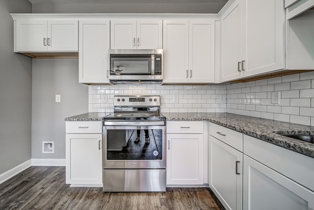 kitchen with white cabinetry, appliances with stainless steel finishes, and dark stone counters