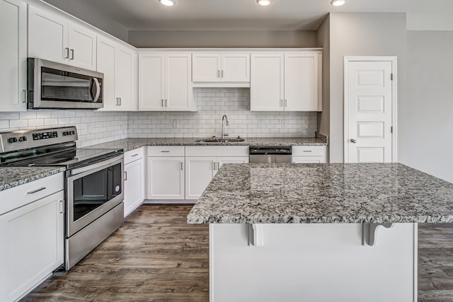 kitchen with sink, a breakfast bar area, stainless steel appliances, and white cabinets