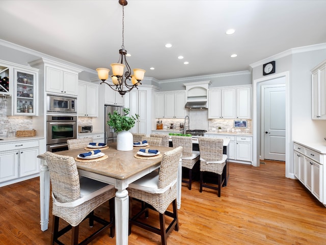 dining area featuring crown molding, light hardwood / wood-style flooring, and a chandelier