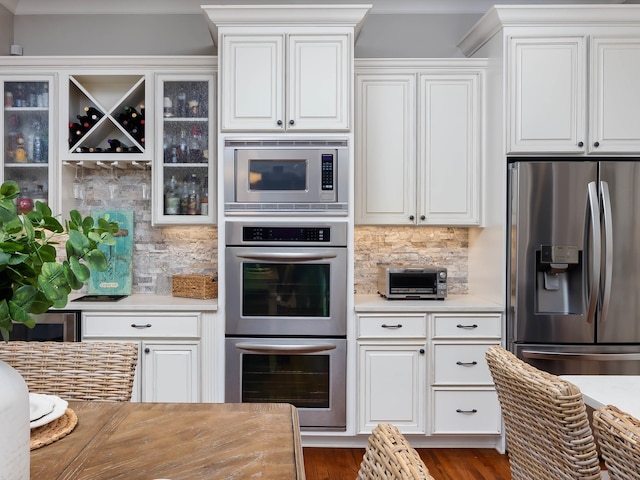 kitchen with white cabinetry, stainless steel appliances, dark wood-type flooring, and tasteful backsplash