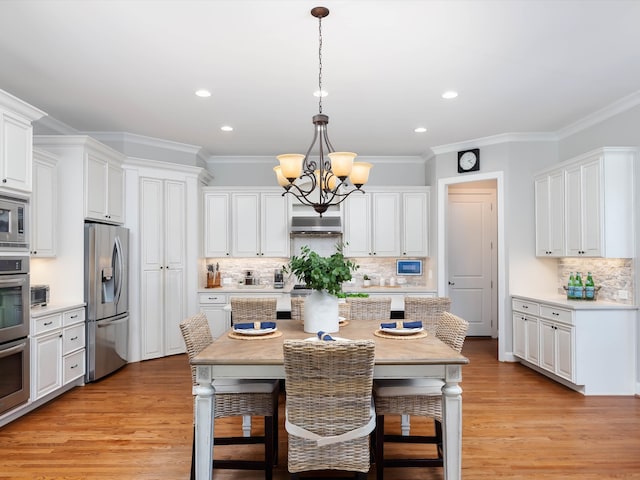 kitchen with white cabinets, light wood-type flooring, decorative light fixtures, and appliances with stainless steel finishes