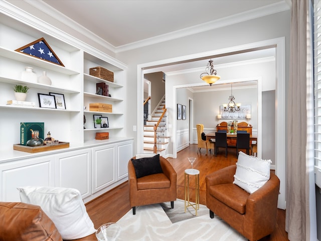 sitting room with crown molding, built in features, an inviting chandelier, and light wood-type flooring