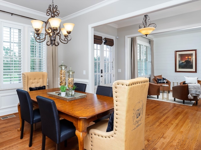 dining area with light hardwood / wood-style floors, crown molding, and a notable chandelier