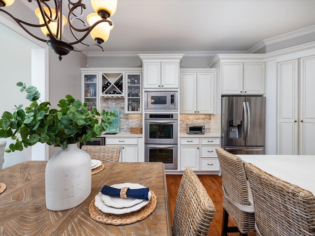 kitchen with decorative backsplash, appliances with stainless steel finishes, white cabinets, and ornamental molding