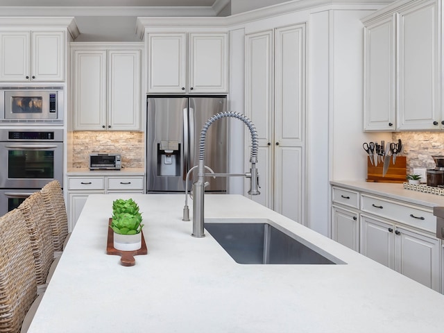 kitchen with white cabinets, decorative backsplash, sink, and appliances with stainless steel finishes