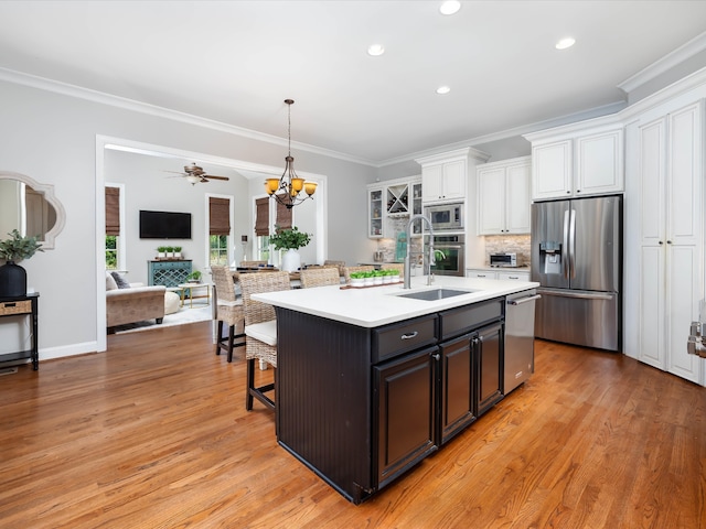 kitchen with appliances with stainless steel finishes, sink, light hardwood / wood-style flooring, white cabinetry, and an island with sink