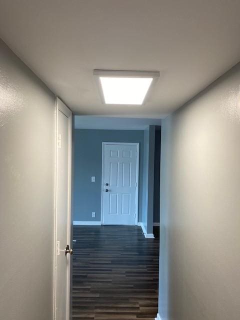 corridor featuring baseboards and dark wood finished floors