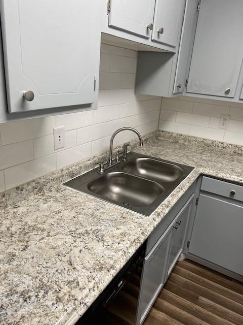 kitchen featuring dark wood-style floors, a sink, backsplash, and gray cabinetry