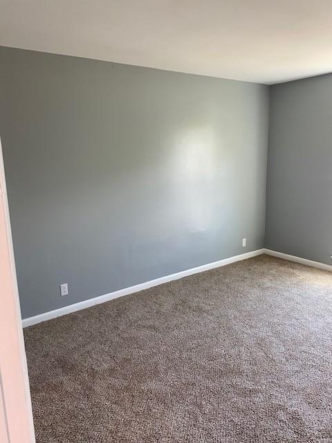 unfurnished room with carpet and baseboards