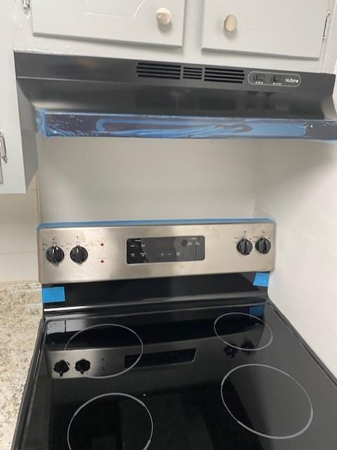 room details featuring stainless steel electric range oven and white cabinets