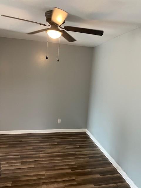 spare room with ceiling fan, baseboards, and dark wood finished floors