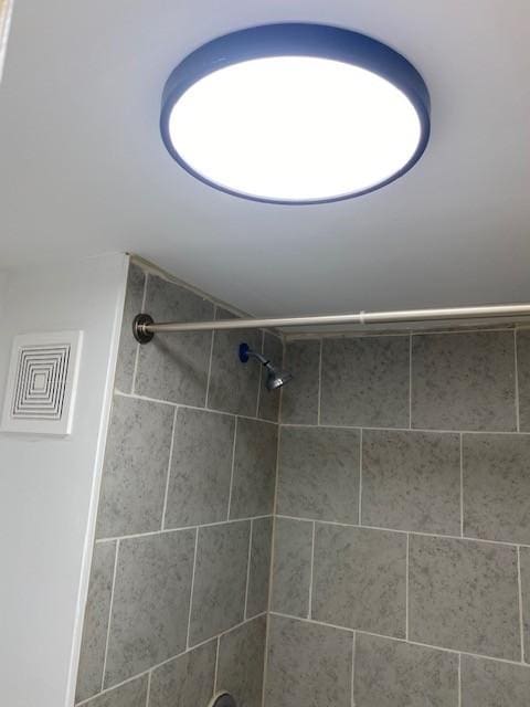 full bathroom featuring visible vents and tiled shower