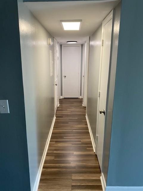 hallway featuring baseboards and dark wood-type flooring