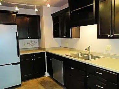 kitchen featuring stainless steel dishwasher, sink, and white fridge