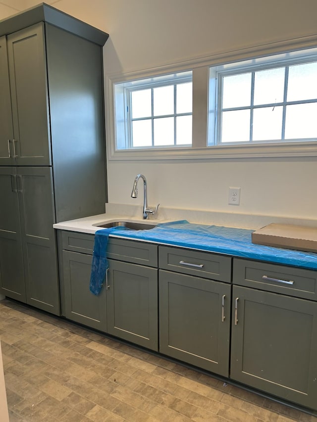 kitchen featuring plenty of natural light, gray cabinets, and a sink