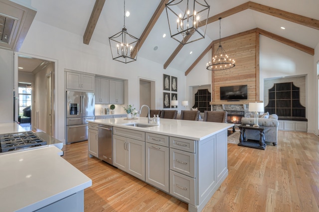 kitchen with a fireplace, high vaulted ceiling, a kitchen island with sink, and sink