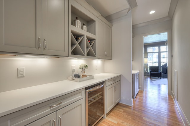 kitchen featuring gray cabinets, light hardwood / wood-style floors, wine cooler, and ornamental molding