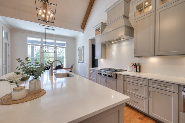 kitchen featuring light hardwood / wood-style flooring, stainless steel gas cooktop, a notable chandelier, premium range hood, and sink