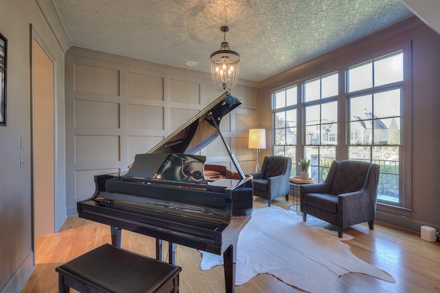 miscellaneous room featuring a textured ceiling, light hardwood / wood-style flooring, ornamental molding, and a notable chandelier