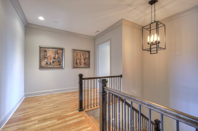 corridor featuring ornamental molding, a notable chandelier, and light hardwood / wood-style floors