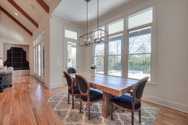 dining area with high vaulted ceiling, a chandelier, light hardwood / wood-style floors, and beam ceiling