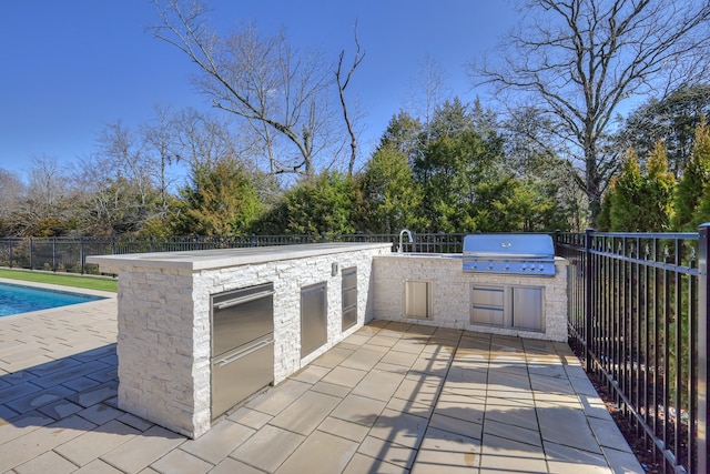 view of patio / terrace with a grill, a fenced in pool, sink, and an outdoor kitchen