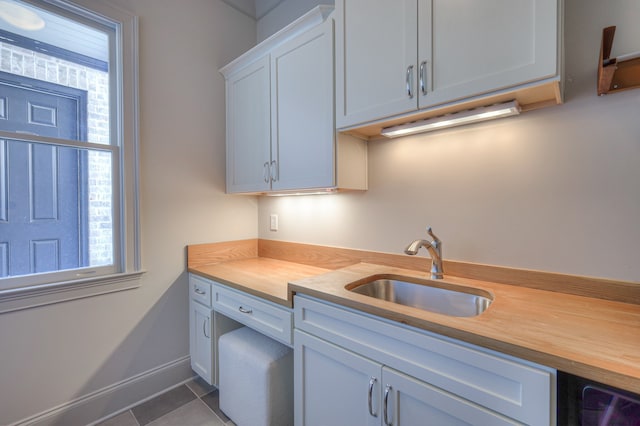 kitchen featuring sink, wood counters, white cabinetry, and dark tile patterned flooring