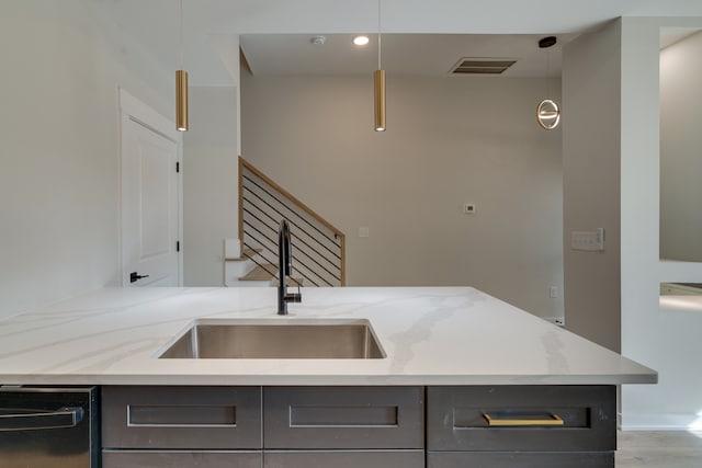 kitchen featuring hardwood / wood-style floors, light stone counters, sink, gray cabinets, and pendant lighting