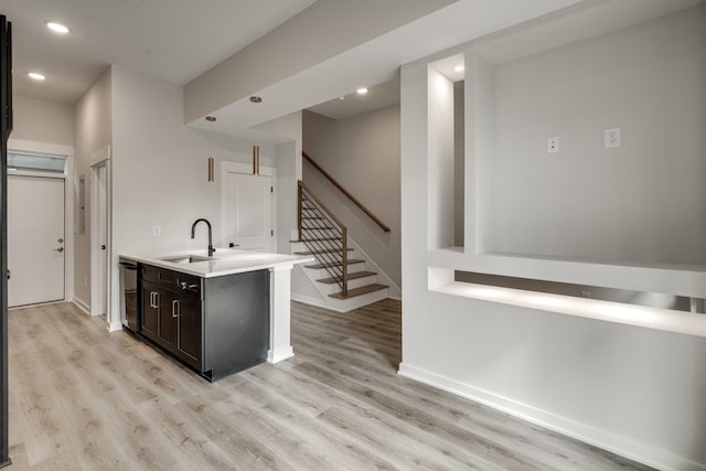 bar with light hardwood / wood-style flooring, stainless steel dishwasher, sink, and decorative light fixtures