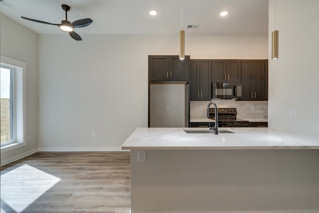 kitchen with light hardwood / wood-style flooring, light stone counters, sink, black appliances, and ceiling fan