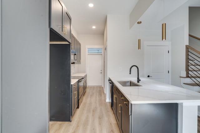 kitchen featuring light hardwood / wood-style flooring, pendant lighting, sink, and light stone countertops