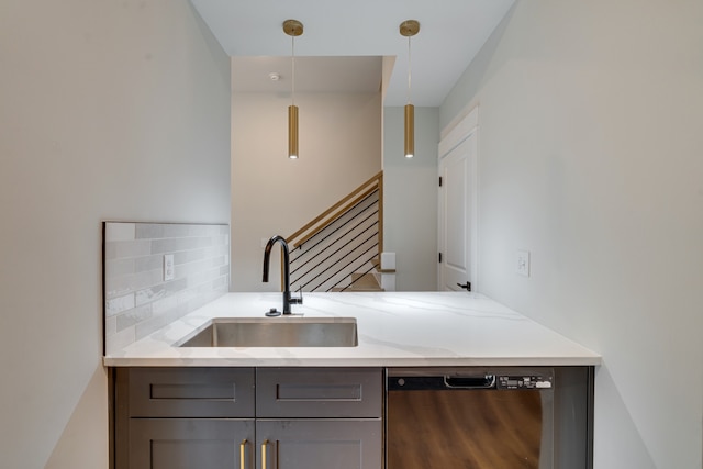 kitchen with pendant lighting, sink, light stone countertops, decorative backsplash, and stainless steel dishwasher