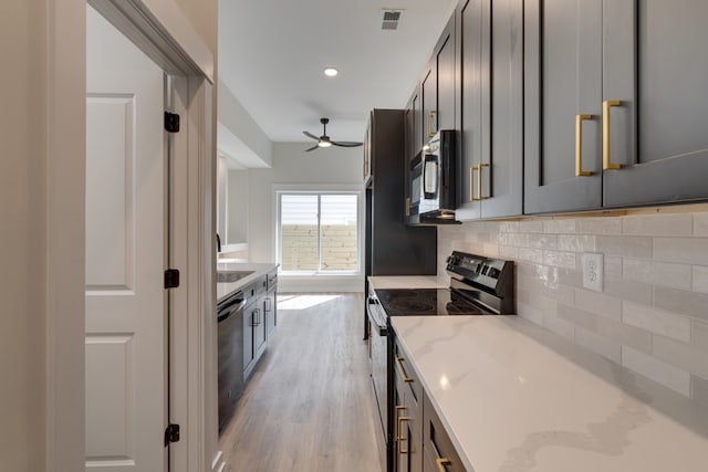 kitchen featuring appliances with stainless steel finishes, light stone countertops, light hardwood / wood-style floors, ceiling fan, and decorative backsplash