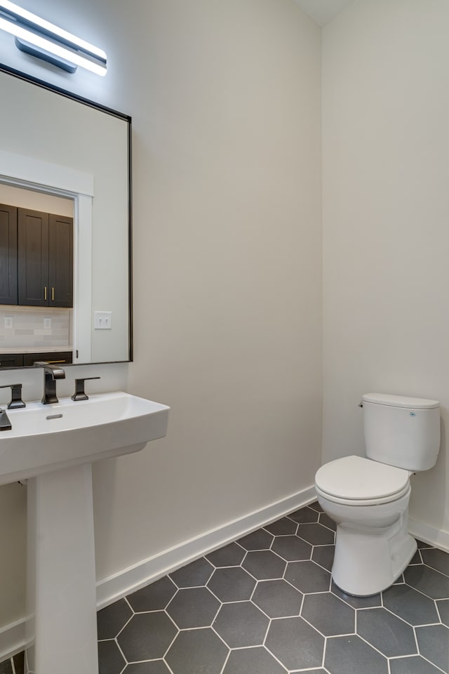 bathroom featuring toilet, backsplash, sink, and tile patterned floors