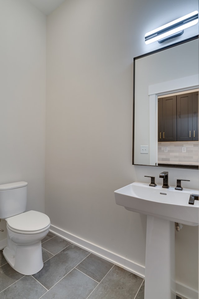 bathroom featuring tile patterned floors, backsplash, toilet, and sink