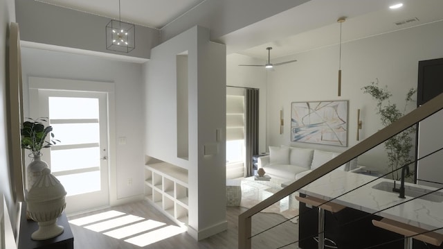 interior space featuring ceiling fan with notable chandelier, wood-type flooring, and a healthy amount of sunlight