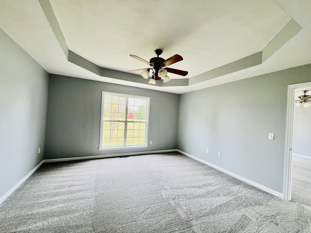 unfurnished room with light carpet, a tray ceiling, and ceiling fan