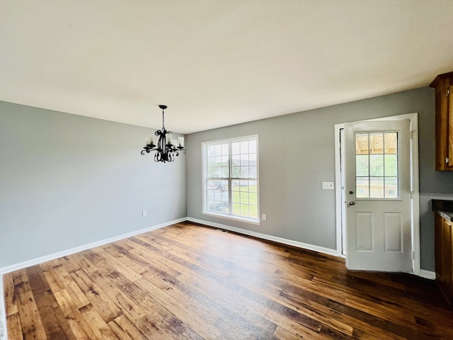 unfurnished dining area featuring dark wood-type flooring and a chandelier