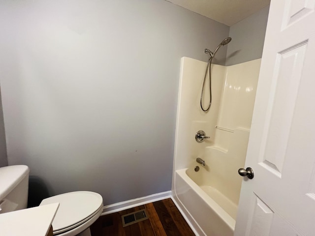 bathroom featuring wood-type flooring, washtub / shower combination, and toilet