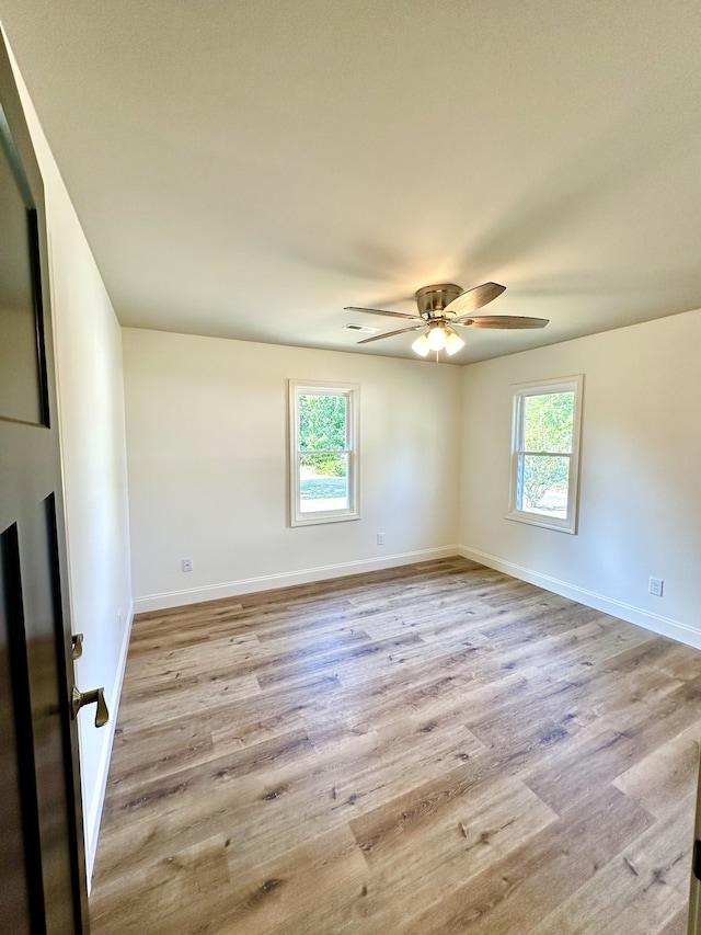 unfurnished room with a wealth of natural light, light hardwood / wood-style floors, and ceiling fan